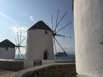 Traditional windmill by sea against sky