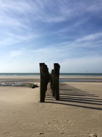 Wooden posts on beach against sky