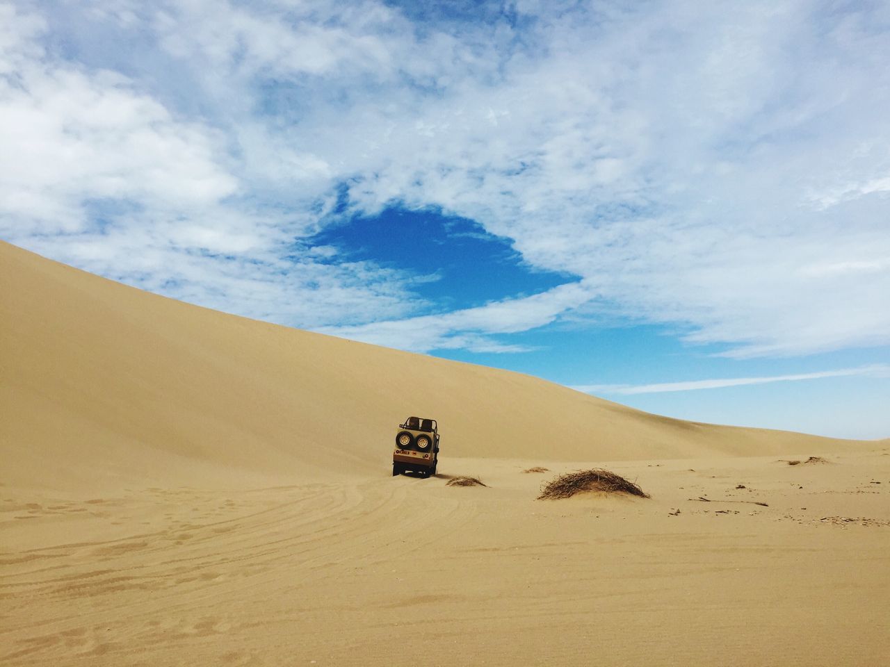 sand, sky, desert, landscape, beach, tranquility, tranquil scene, cloud - sky, scenics, arid climate, sand dune, nature, remote, cloud, transportation, non-urban scene, beauty in nature, day, travel, outdoors