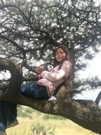 Full length of woman sitting on tree