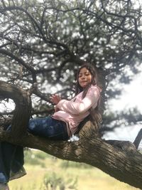 Full length of girl sitting on tree