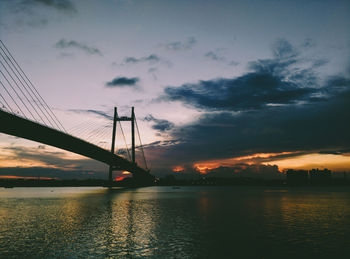Low angle view of suspension bridge over river against sky