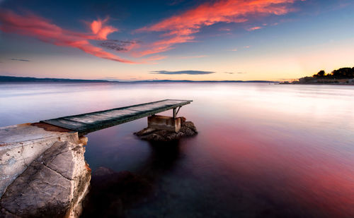 Pier over sea against sky during sunset