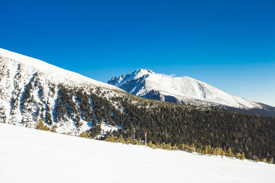 Scenic view of snowcapped mountains against clear blue sky