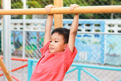 Boy hanging on metal in playground