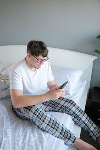 Side view of woman sitting on bed at home