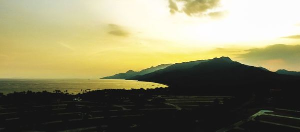 Scenic view of sea and silhouette mountains against sky