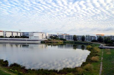 Buildings by river against sky in city