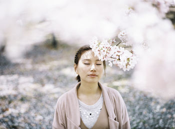 Young woman standing by flowers