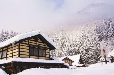 Snow covered landscape and houses against sky