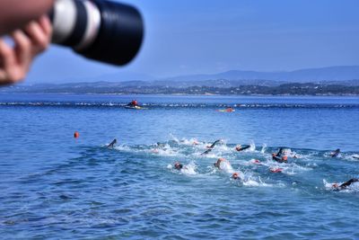 People swimming in sea against sky