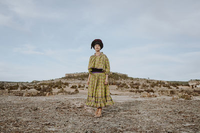 Full length of young woman standing on land against sky