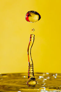 Close-up of water splashing against yellow background
