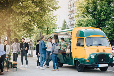 Male and female customers standing by food truck