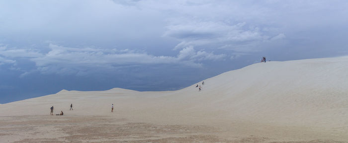 People on arid landscape against sky