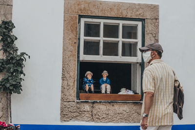 Full length of father with daughter standing against window