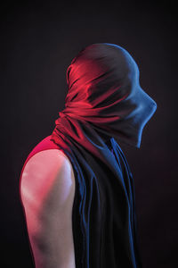 Side view of man covering face against black background