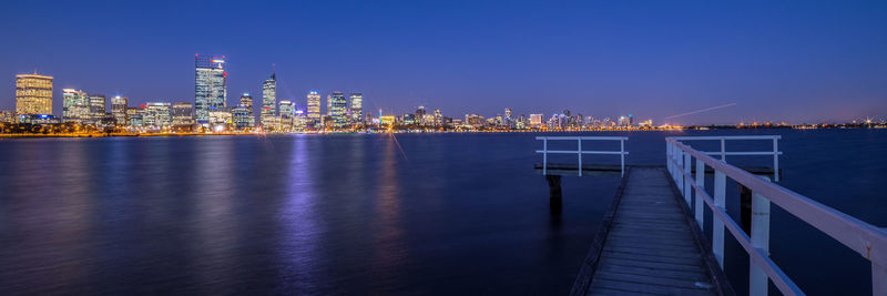 Panoramic view of illuminated city by river at night