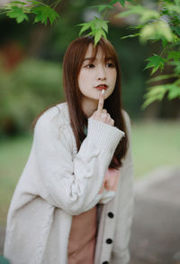 Portrait of young woman standing against trees