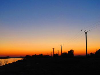 Silhouette electricity pylon against romantic sky at sunset