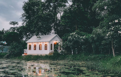House by trees and building against sky