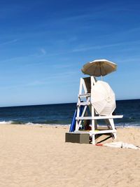 Deck chairs on beach against sky