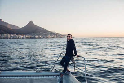 Full length portrait of young man standing on sea against clear sky