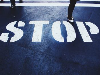 Low section of people standing near stop sign on street