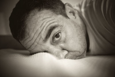 Close-up portrait of man lying on bed at home