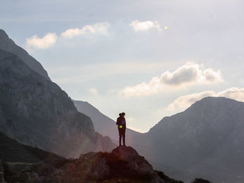 Rear view of man standing on rocks against mountain