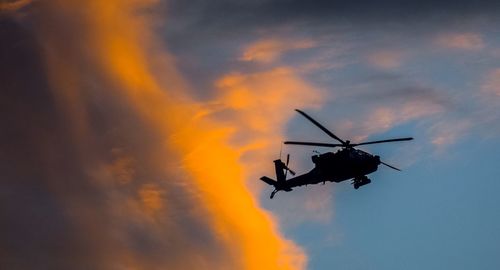 Low angle view of silhouette helicopter against sky during sunset