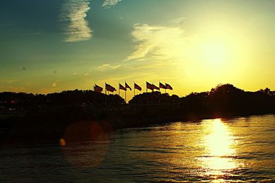 Silhouette trees by lake against sky during sunset