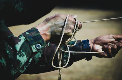 Cropped hands of army soldier pulling rope