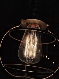 Close-up of illuminated light bulb against black background