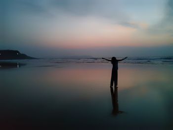 Silhouette person standing on beach against sky during sunset