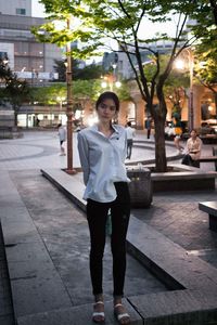 Portrait of woman standing on footpath in city