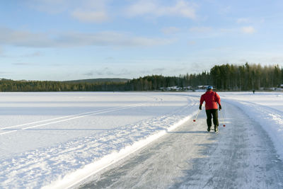 Rear view of man walking on snow covered road