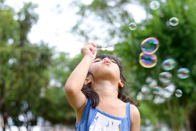 Cute girl blowing bubbles at park