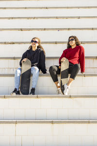 Full length of woman sitting against wall