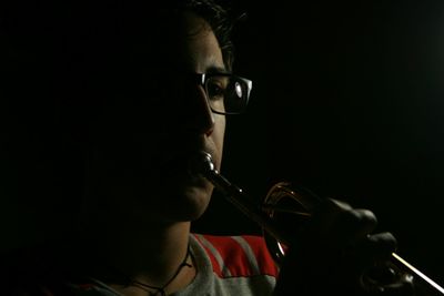 Close-up of man playing trumpet against black background