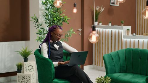 Young woman using laptop while sitting on sofa at home