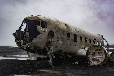 Abandoned airplane on airport runway against sky