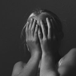 Low angle view of young woman covering face against ceiling