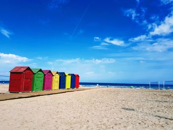 Multi colored huts at beach against blue sky