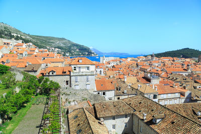 High angle view of houses in town against clear blue sky