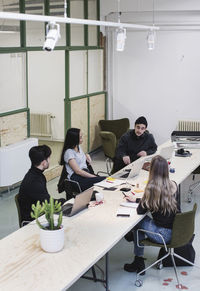 High angle view of four entrepreneurs discussing at desk in creative office