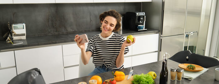 Portrait of smiling young woman standing in kitchen