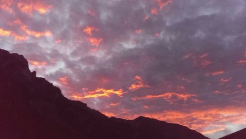 Scenic view of mountains against cloudy sky at sunset