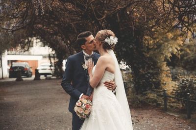 Couple holding hands while standing against plants