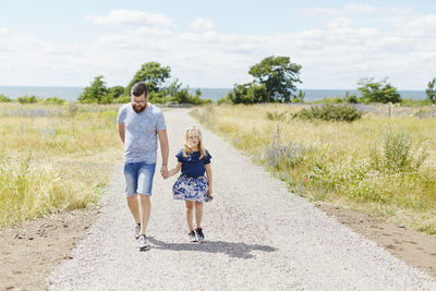 Full length of a couple standing on dirt road against sky